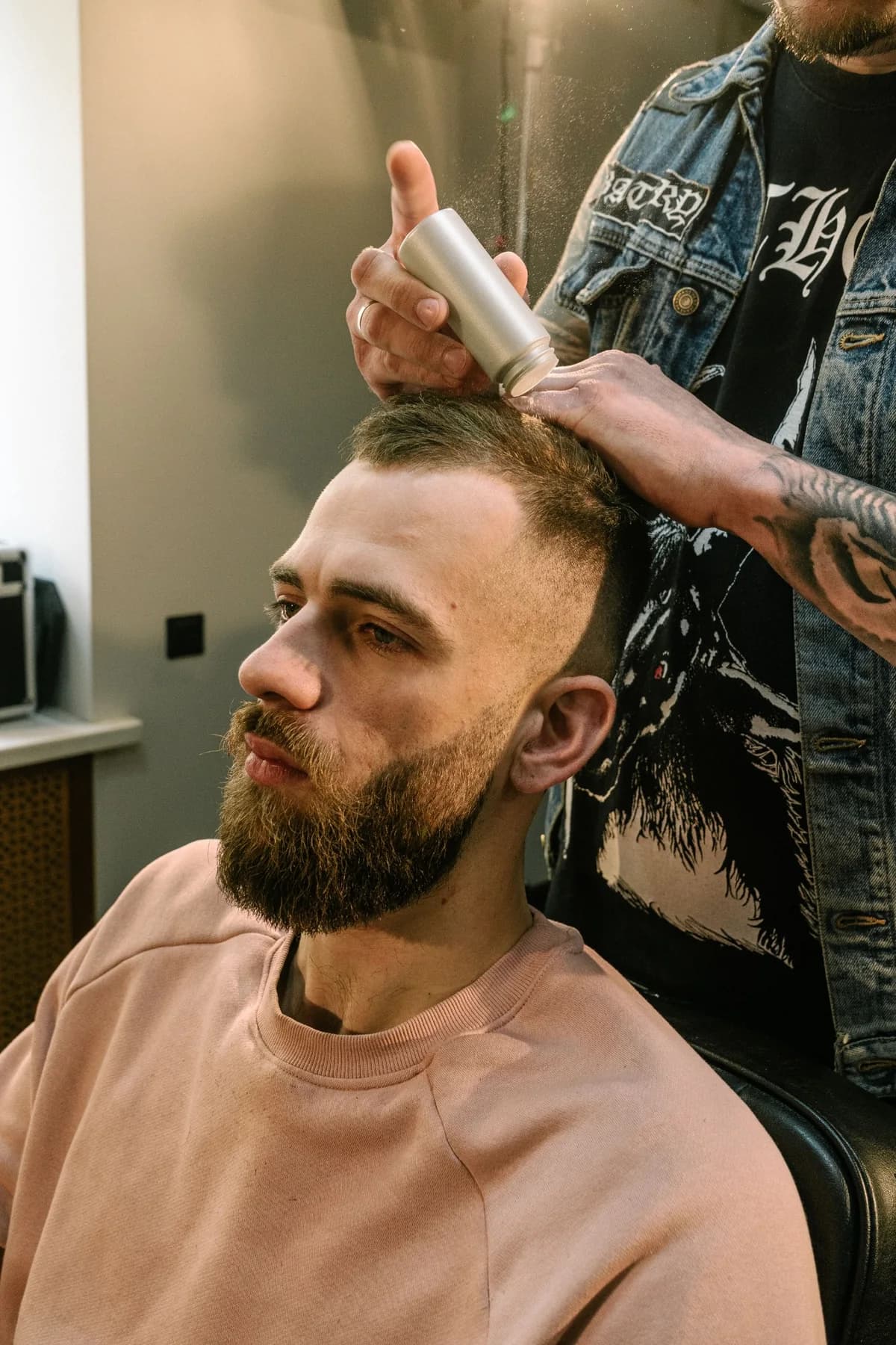 Barber applying loose hair-building fibers during a grooming session